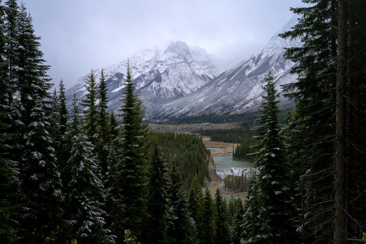 Rivière coulant au milieu de forêts et montagnes blanches, au Canada