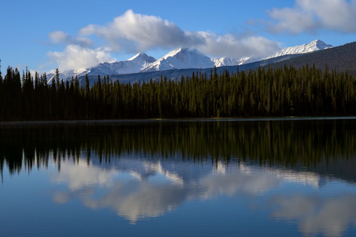 Lac entouré de forêt et de montagnes enneigées, au Canada.