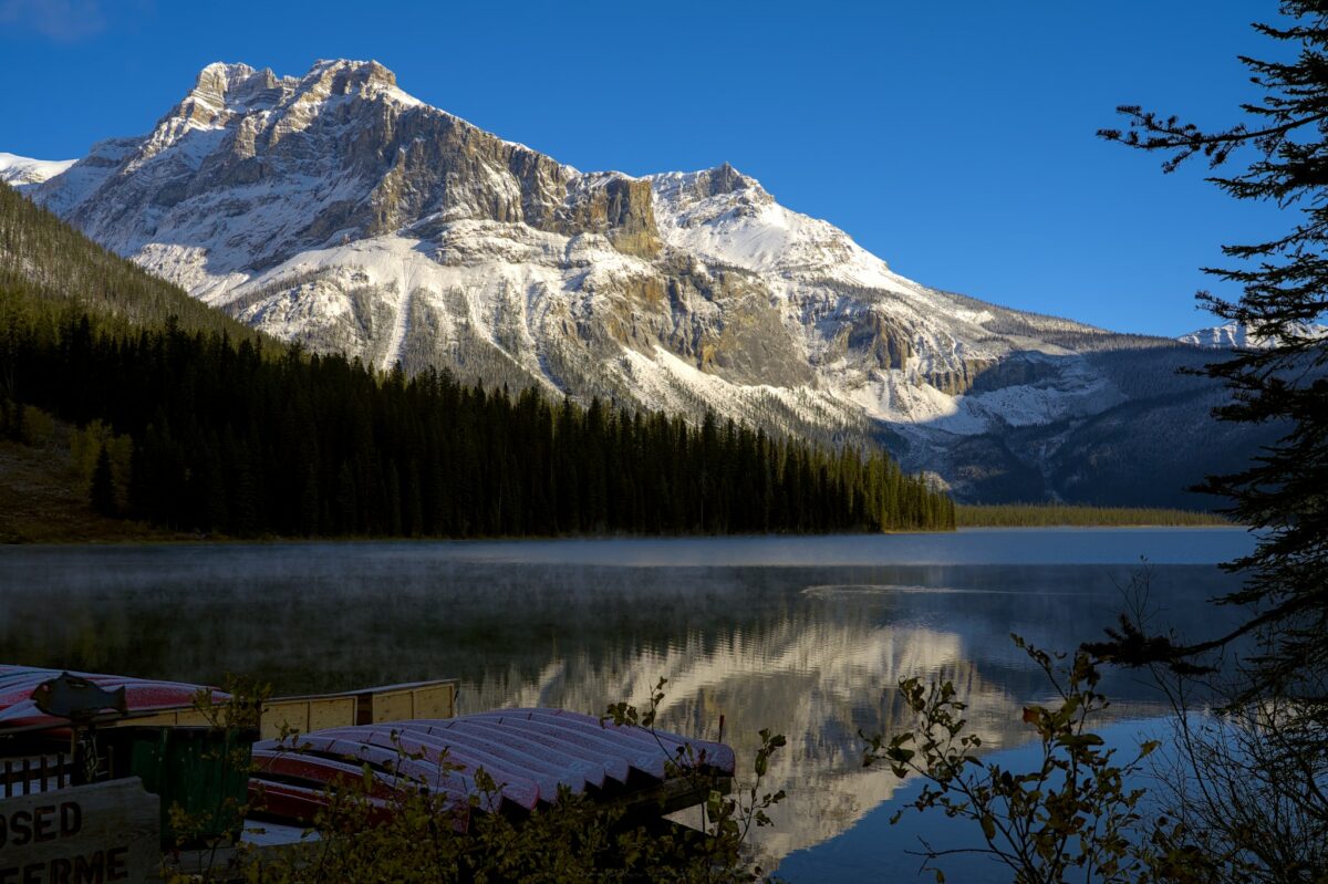 Lac entouré de forêt et de montagnes enneigées, au Canada.